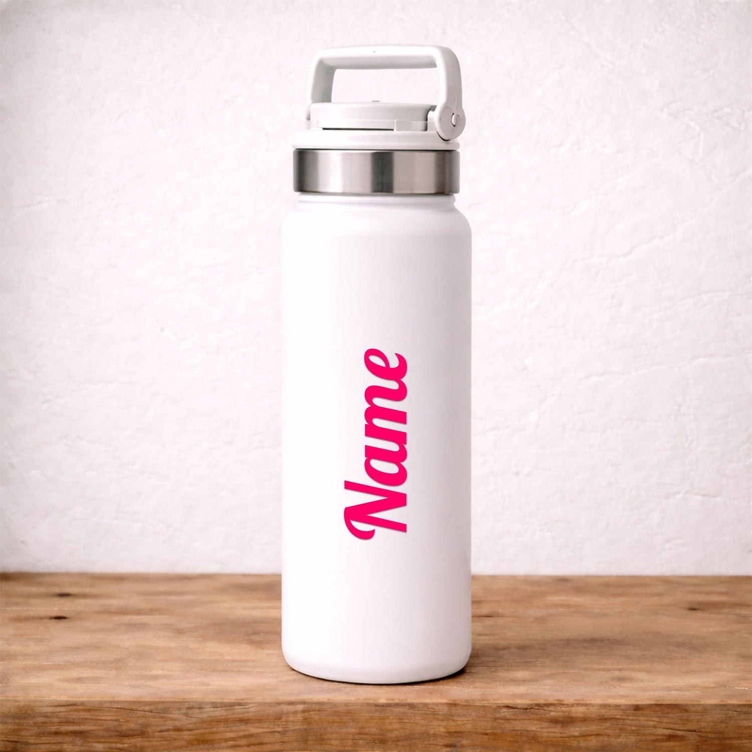 White water bottle with pink custom 'Name' decal placed on it, placed on a wooden surface with a light background