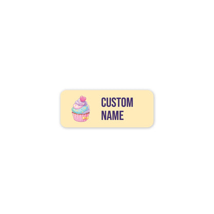 A rectangular custom label with rounded corners, featuring a pastel cupcake illustration on the left and the text 'CUSTOM NAME' in dark purple on the right, set against a solid white background.