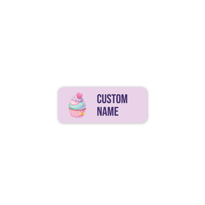 A customisable rectangular label with rounded corners, featuring a pastel pink cupcake illustration on the left and the text 'CUSTOM NAME' in dark purple on the right, set against a solid white background.