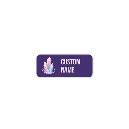 Custom name label with rounded corners on a white background. The label is purple with a pink and blue crystal illustration and pink text reading 'CUSTOM NAME'.