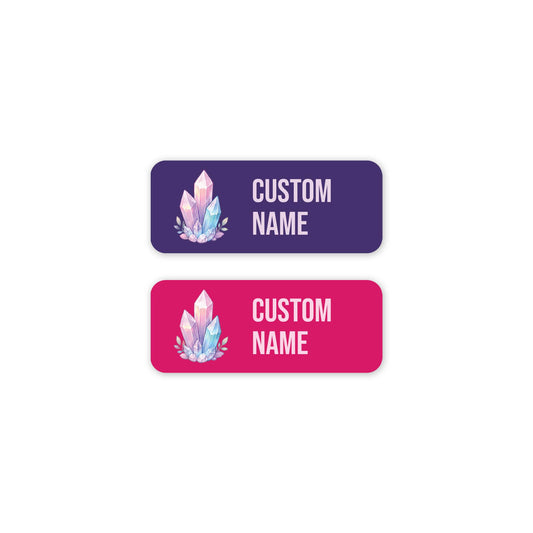 Two custom name labels with rounded corners on a white background. The top label is purple with a pink and blue crystal illustration and pink text reading 'CUSTOM NAME'.