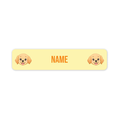 A pale yellow rectangular label with rounded corners, featuring two cartoon puppy faces at the left and right edges and the word "NAME" in orange centered between them, on a white background.