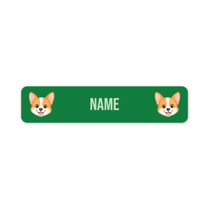 A green rectangular pet nameplate with rounded corners, featuring two cartoon corgi faces on the left and right sides and the word 'NAME' in the center for personalization.
