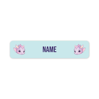 A horizontal light blue personalised name label with rounded corners, featuring two cute pink and purple dragon illustrations on the left and right sides and the word 'NAME' in the centre for customisation.