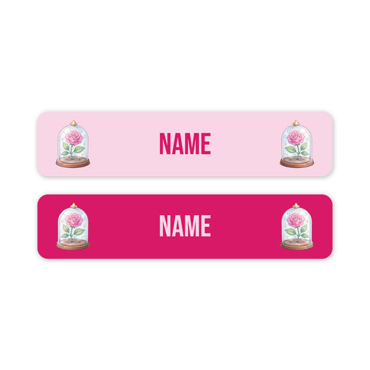 Two horizontal rectangular name labels on a white background. The top label is light pink with the word 'NAME' in pink and pink lettering, flanked by illustrations of pink roses under glass domes.